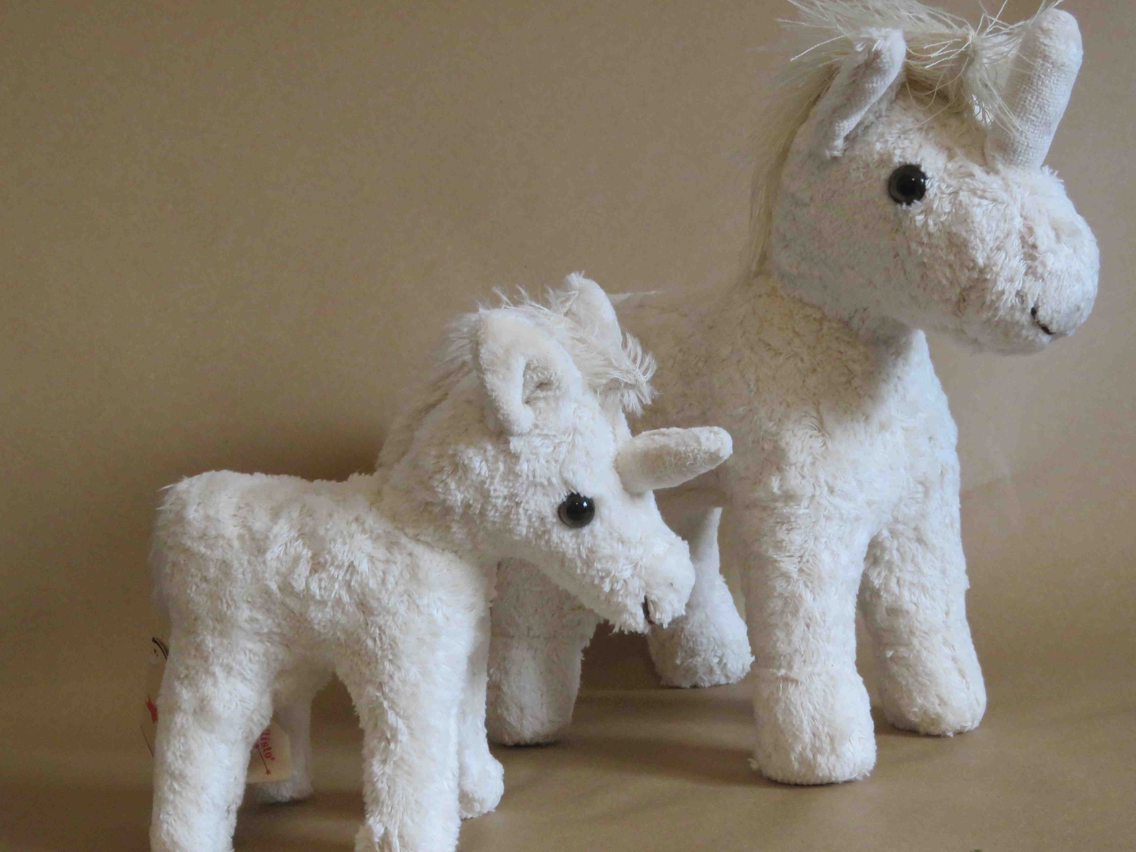 Auf dem BIld sind ein großes und ein kleines Einhorn Plüschtier nebeneinander stehend abgebildet.  Sie sind Kuscheltiere aus Bio Baumwolle 